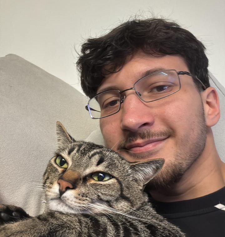 Veterinário sorrindo com um gato no colo, no sofá de casa